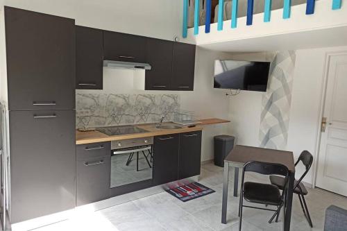 une cuisine avec des armoires noires, une table et des chaises dans l'établissement Gite La Floiracaise, à Floirac