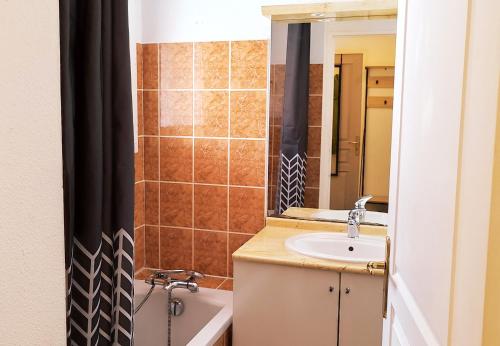 une salle de bain avec un lavabo, une baignoire et un miroir dans l'établissement Appartement Le Sorbier 4 personnes, à Briançon