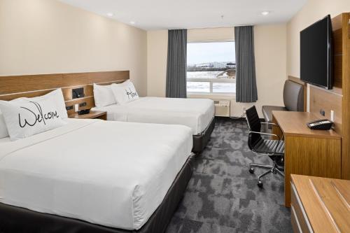 a hotel room with two beds and a desk at Home Inn & Suites - Swift Current in Swift Current