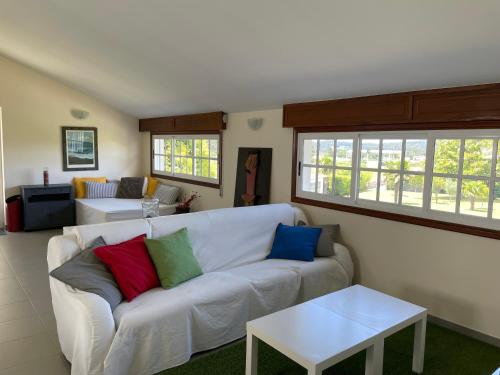 a living room with a white couch with colorful pillows at Tranquilidad con piscina en Casa Nantes en Sanxenxo in Sanxenxo