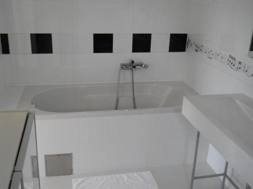 a white bath tub in a bathroom with black and white tiles at Mala vila Punta Skala in Petrcane