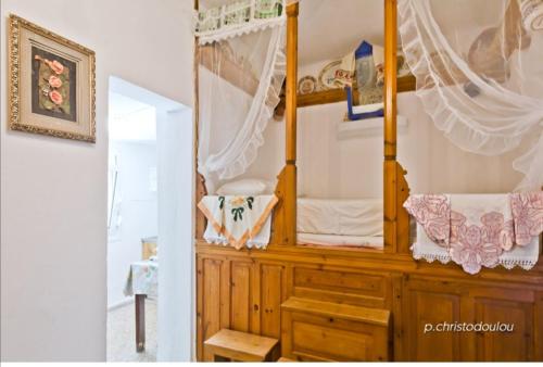 Cette chambre comprend un lit avec des rideaux et un miroir. dans l'établissement Rou Garden House, à Karpathos