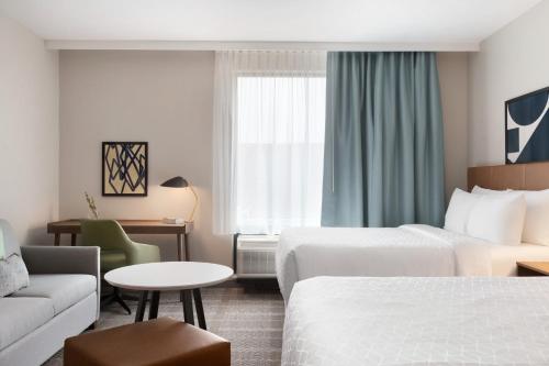 a hotel room with two beds and a couch at Staybridge Suites Rochester - Mayo Clinic Area by IHG in Rochester