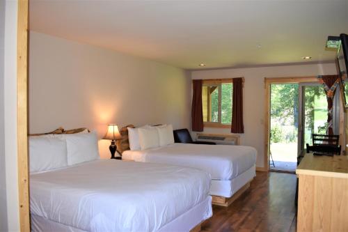 um quarto de hotel com duas camas e uma varanda em Methow River Lodge em Winthrop