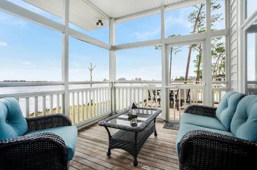 a screened in porch with two chairs and a table at Eagle Cottages at Gulf State Park in Gulf Shores