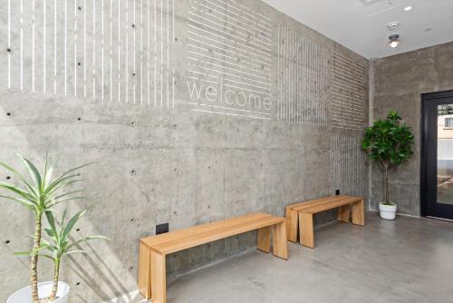 a lobby with two wooden benches against a concrete wall at The Metric - Los Angeles Downtown in Los Angeles