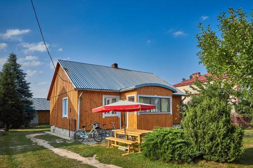 Casa de madera con mesa de picnic y sombrilla en ROZTOCZE Wiejski Domek, en Horyniec