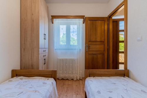 a bedroom with two beds and a mirror and a window at Apartment Jurasić in Orlec
