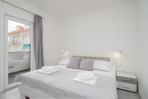 a white bedroom with a large white bed and a mirror at Apartments Pelja in Trogir