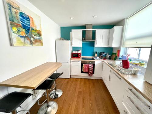 une cuisine avec des placards blancs et une table en bois dans l'établissement 4 bedroomed maisonette in City Centre, near Barbican & Seafront, à Plymouth