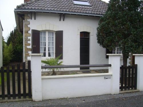 une maison blanche avec une clôture noire et blanche dans l'établissement maison à 400 mètres de la plage, à La Baule
