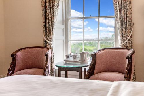 a bedroom with two chairs and a table and a window at Best Western Limpley Stoke Hotel in Bath