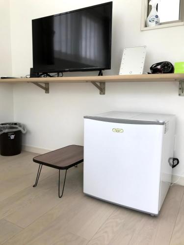 a small refrigerator and a tv on a wall at Blue House in Nago