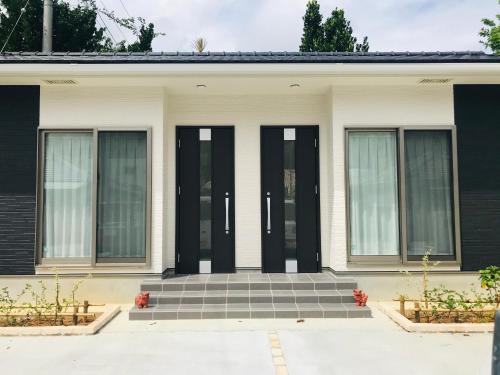 Casa blanca con puertas y ventanas negras en Blue House, en Nago