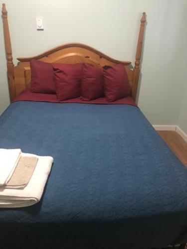 a bed with red pillows and a blue comforter at Hillside Motel in Lake George