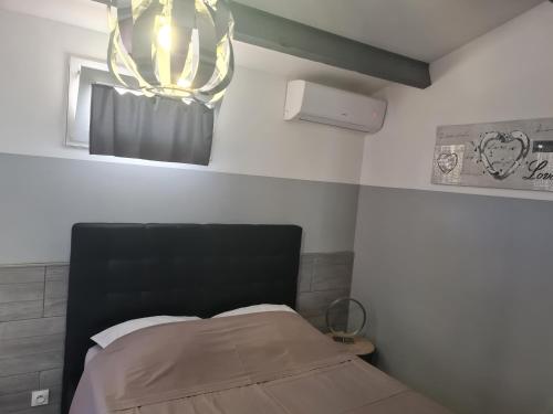 um quarto com uma cama e um lustre em Chambre cosy avec terrasse em Arles
