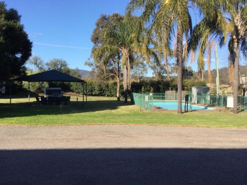 a park with a pool and a tent and palm trees at Aberdeen Motel in Aberdeen