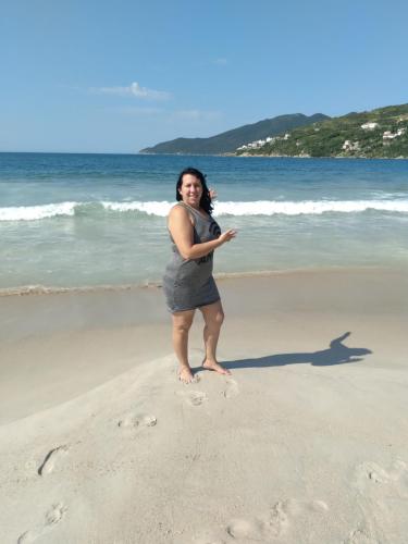 una mujer parada en la arena en la playa en Hospedagem Brilho do Sol, en Arraial do Cabo