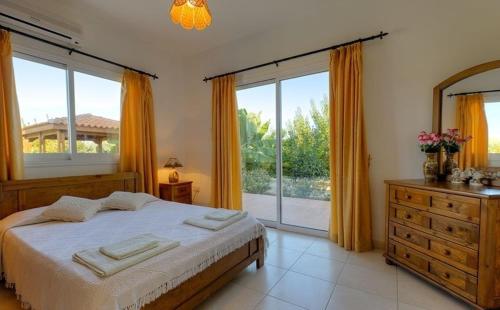 a bedroom with a bed and a large window at Peyia Villas Cyprus in Peyia