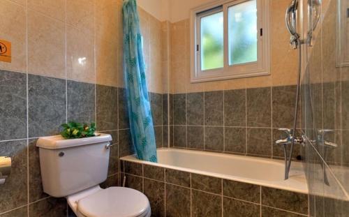 La salle de bains est pourvue de toilettes, d'une baignoire et d'une fenêtre. dans l'établissement Peyia Villas Cyprus, à Peyia