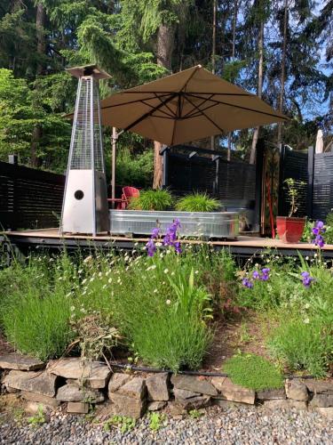 a garden with an umbrella and some flowers at Salt Spring Carriage House B&B in Ganges