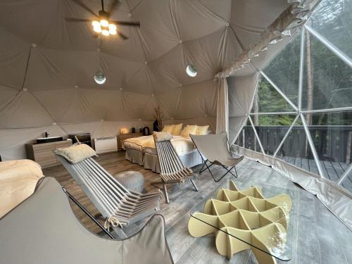 Una habitación con una tienda de campaña con sillas y una cama en TOCORO. Mt.Fuji CAMP&GLAMPING en Fujikawaguchiko