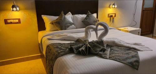 two swans are on a bed in a hotel room at Le Supreme Inn (the lap of luxury) in Puducherry
