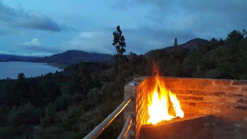 a fire in a brick wall with a view of a lake at Abadia de Tomine in Guatavita
