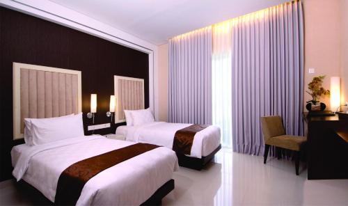 a hotel room with two beds and a desk at Gallery Prawirotaman Hotel in Yogyakarta