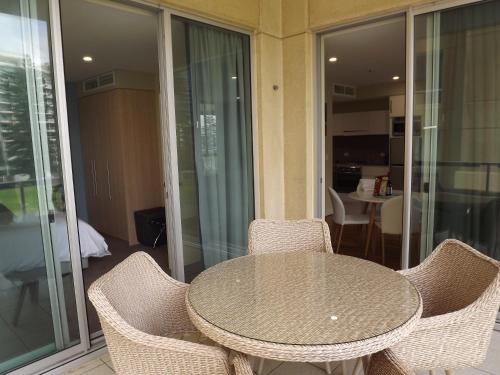 a glass table and chairs on a balcony at Beachside Luxury Apartments One & Two Bedroom in Beachfront Oaks Pier Building in Glenelg