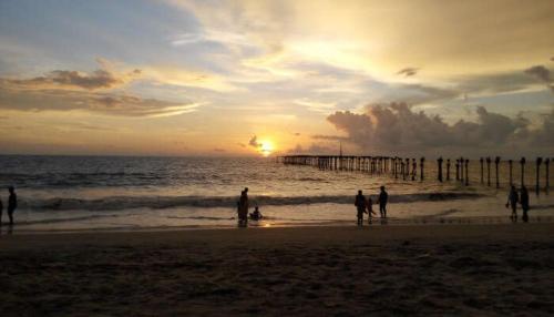 a group of people standing on the beach at sunset at Oceana Hills Residency in Alleppey