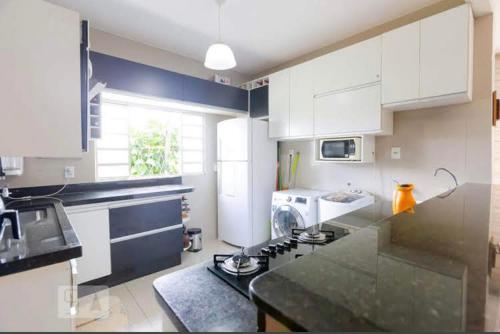 a kitchen with white cabinets and a stove top oven at Caso com piscina AQUECIDA, há 900 metros do Iguatemi shopping in Brasília