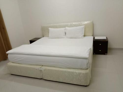 Bett mit weißer Bettwäsche und Kissen in einem Zimmer in der Unterkunft JANDOUL SALALAH جندول صلاله in Salalah