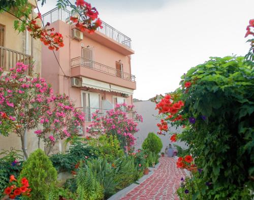 a brick path in front of a pink building with flowers at Margarita Studios in Palaiochora