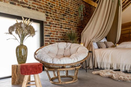 a bedroom with a chair and a bed and a brick wall at De Hoeveschuur in Riemst