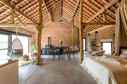 a brick walled room with a bed and a table at De Hoeveschuur in Riemst