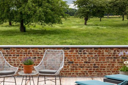 a brick wall with three chairs and a table at De Hoeveschuur in Riemst