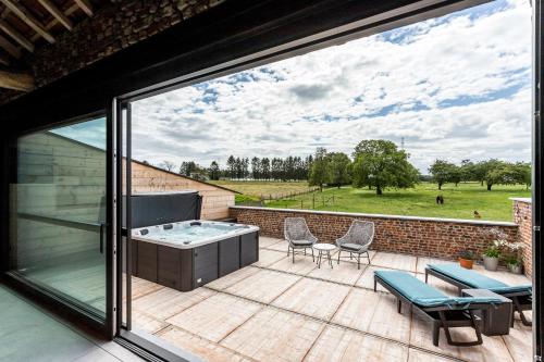 a patio with a hot tub and chairs on a deck at De Hoeveschuur in Riemst
