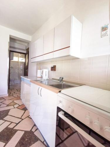 a kitchen with white cabinets and a sink at Rumenović in Stanići