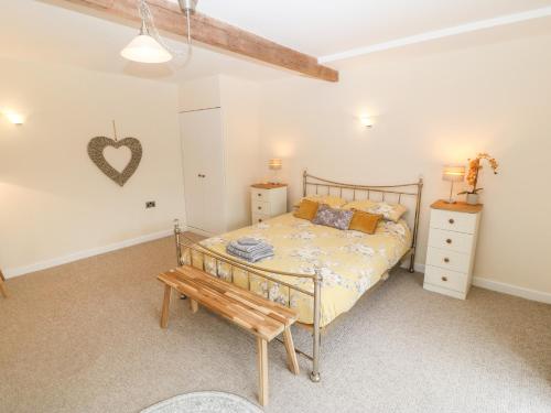 een slaapkamer met een bed en een houten bank bij Llofft Yr Yd in Caernarfon