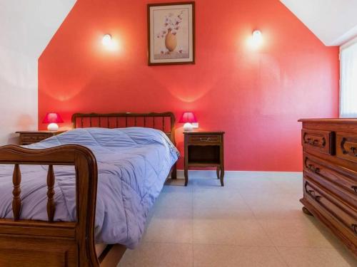 1 dormitorio con cama y pared roja en Gîte Saint-Lyphard, 3 pièces, 4 personnes - FR-1-306-1132, en Saint-Lyphard