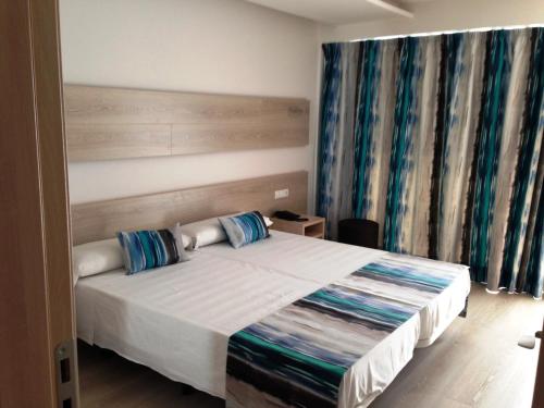 a bedroom with a large bed with blue curtains at Hotel Gracia in El Arenal