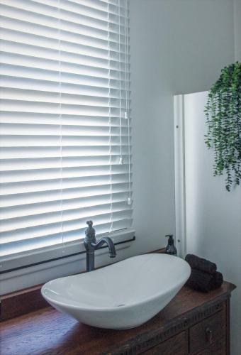 a white bath tub sitting in front of a window at 5-Star OLD POST OFFICE HOLIDAY HOME - 5-7-Bedroom Art Deco Elegance in Owhango