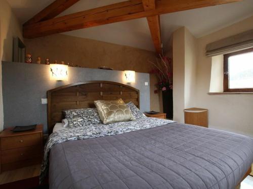 a bedroom with a large bed with a wooden headboard at Ancien pigeonnier restauré avec terrasse, terrain clos et équipements bébé à Sarlanges, Retournac - FR-1-582-167 in Retournac