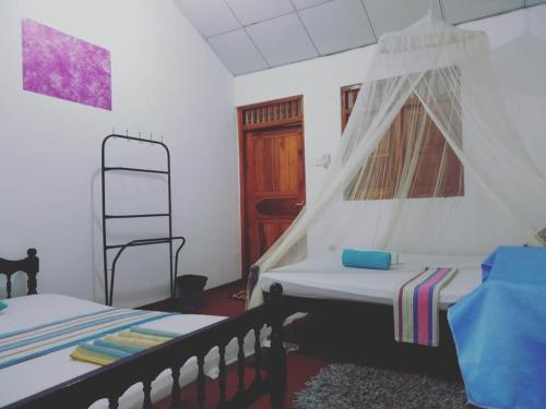 a bedroom with two beds and a window and a ladder at Viraj's Garden in Tangalle