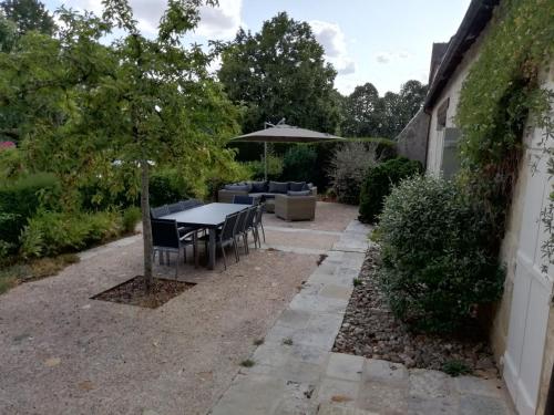 a patio with a table and chairs and an umbrella at Gîte haut de gamme près de l'Abbaye de Noirlac - Séjour tout confort avec jardin et terrasses - FR-1-586-13 in Bruère-Allichamps