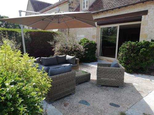 a patio with two chairs and an umbrella at Gîte haut de gamme près de l'Abbaye de Noirlac - Séjour tout confort avec jardin et terrasses - FR-1-586-13 in Bruère-Allichamps