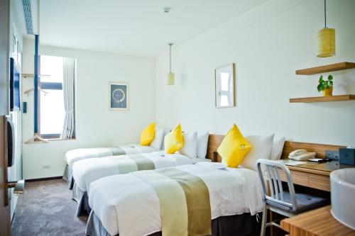 a row of beds in a room with yellow pillows at Bee House by Cosmos Creation - Taipei Main Station in Taipei