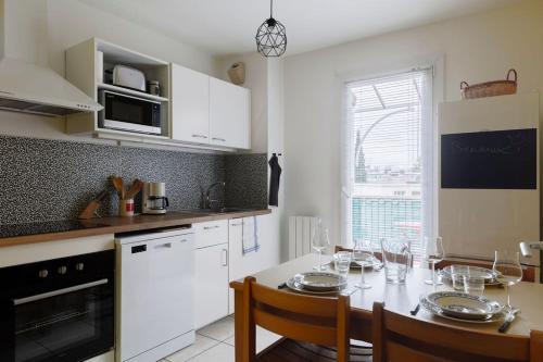 une cuisine avec une table avec des chaises et une salle à manger dans l'établissement Nicolas III, parking privé, clim, balcon, à Grenoble