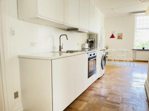 uma cozinha branca com um lavatório e uma máquina de lavar louça em aday - Aalborg mansion - Open bright apartment with garden em Aalborg